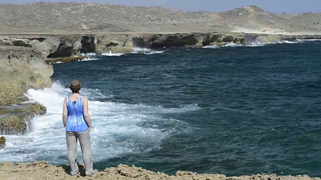 女人走在海滩边，海岸岩石视频素材