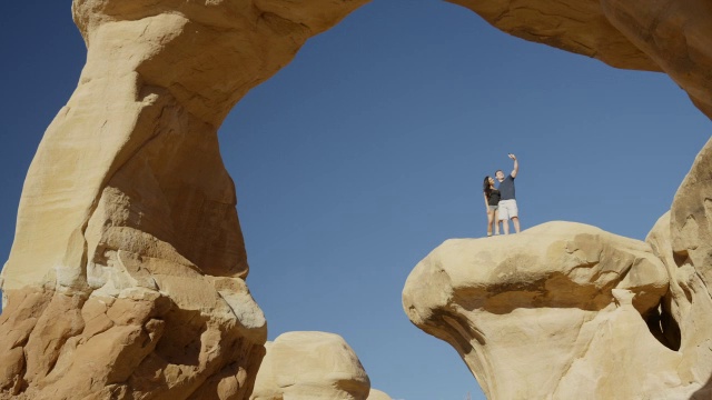 宽平移低角度拍摄的夫妇摆姿势自拍在岩层/ Escalante，美国犹他州视频素材