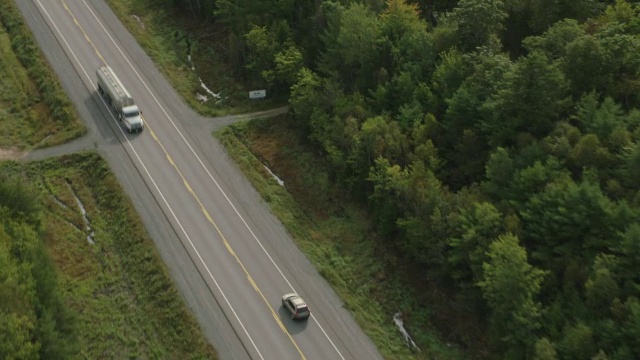 航拍汽车行驶在乡村道路上。森林里的树。视频素材