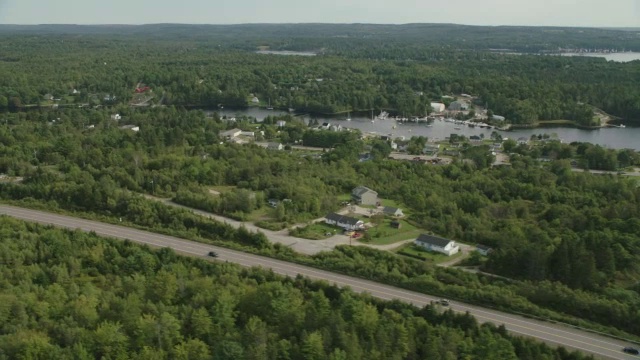 汽车在乡村道路上行驶的空中跟踪镜头。林中的树林中的树湖。视频素材