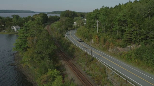 汽车在乡村或农村地区道路上行驶的天线。林中的树林中的树湖。铁轨。视频素材