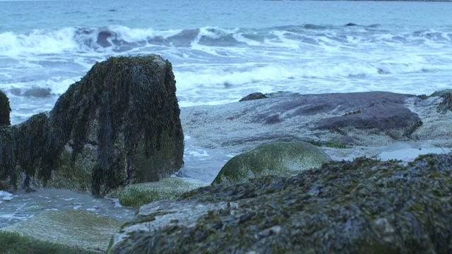 中等角度的波浪撞击海岸岩石。可能是海滩。可能是湖泊或海洋。视频素材