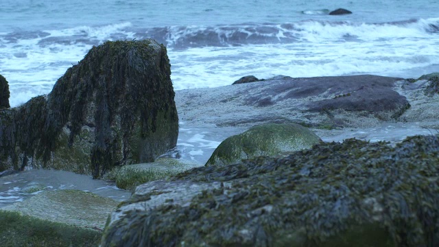 中等角度的波浪撞击海岸岩石。可能是海滩。可能是湖泊或海洋。视频素材