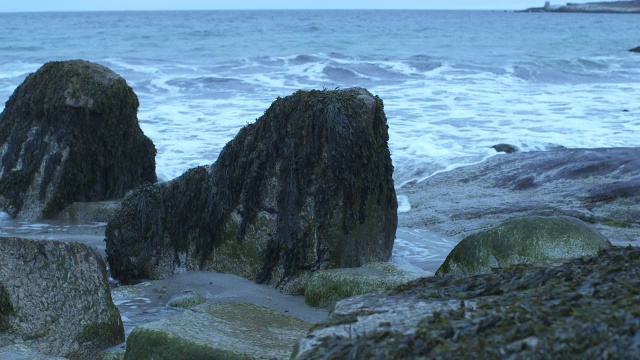 中等角度的波浪撞击海岸岩石。可能是海滩。可能是湖泊或海洋。视频素材