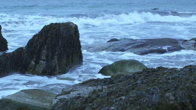 中等角度的波浪撞击海岸岩石。可能是海滩。可能是湖泊或海洋。视频素材