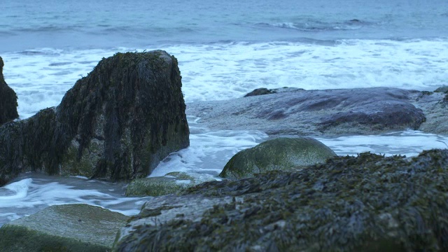 中等角度的波浪撞击海岸岩石。可能是海滩。可能是湖泊或海洋。视频素材