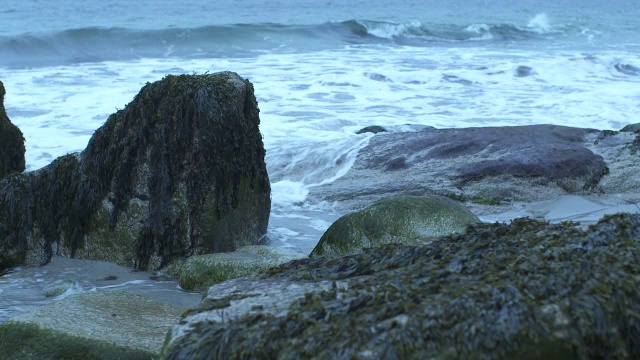 中等角度的波浪撞击海岸岩石。可能是海滩。可能是湖泊或海洋。视频素材