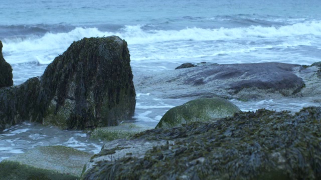 中等角度的波浪撞击海岸岩石。可能是海滩。可能是湖泊或海洋。视频素材