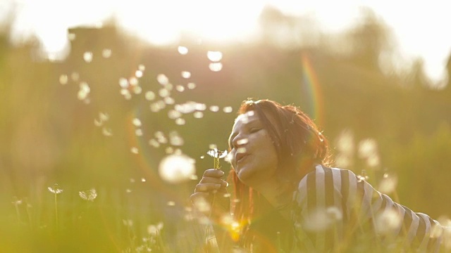 悠闲的女人在公园里吹蒲公英视频素材