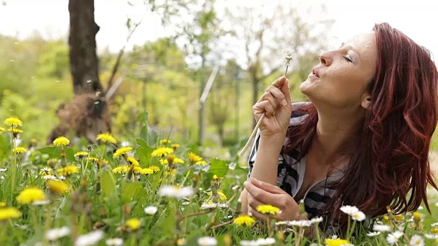 悠闲的女人在公园里吹蒲公英视频素材