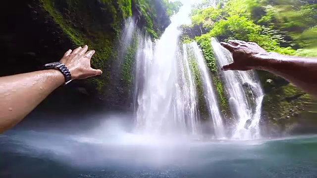 在旅行度假期间，从个人的角度享受在印度尼西亚的野生自然的惊人瀑布下游泳。视频素材