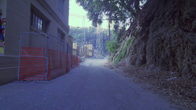 一辆闪亮的红色跑车穿过一条小巷，停在一座多层建筑和一座土山之间。视频素材