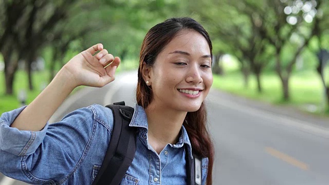 亚洲女性与明亮的背包和自由旅行者女人站着举起手臂，享受美丽的自然视频素材