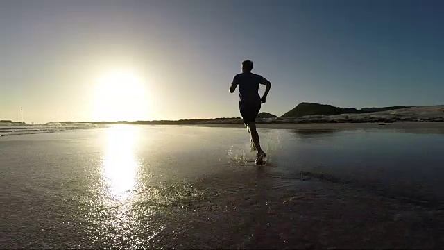 夕阳西下，一位老人在美丽的海滩上慢跑视频素材