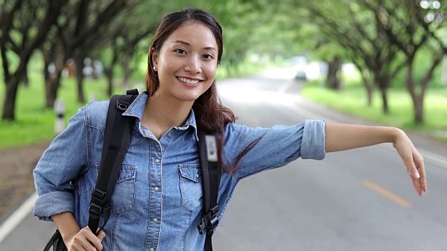 亚洲女性与明亮的背包和自由旅行者女人站着举起手臂，享受美丽的自然视频素材