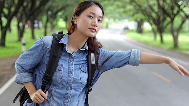 亚洲女性与明亮的背包和自由旅行者女人站着举起手臂，享受美丽的自然视频素材