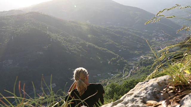 女性徒步旅行者在山谷上方放松，喝着水视频素材