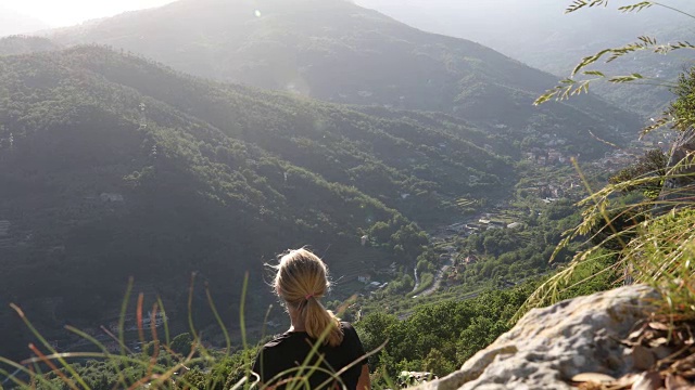 女性徒步旅行者在山谷上方的岩石上放松，用数码平板电脑视频素材