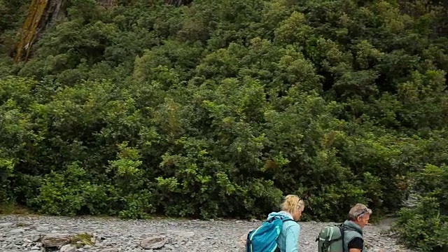 徒步旅行的夫妇沿着河床经过瀑布视频素材