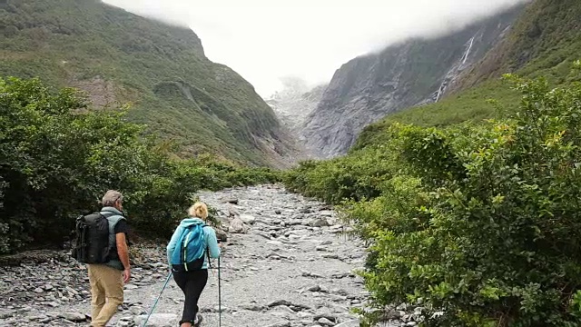 徒步旅行的夫妇沿着河床经过瀑布视频素材