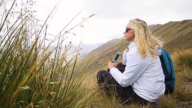 女徒步旅行者在山坡的草地上休息视频素材