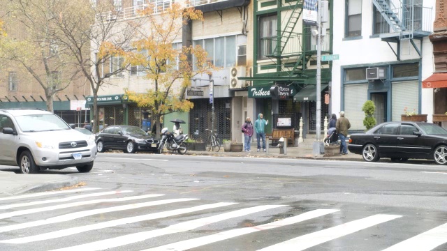 中等角度的城市街道。可见汽车、行人和店面。视频素材