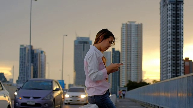 迷人的女人在夜间城镇的街道上使用手机视频素材