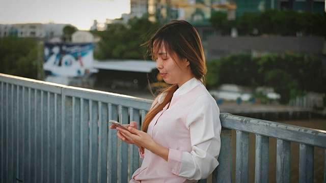 迷人的女人在夜间城镇的街道上使用手机视频素材