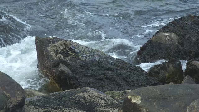 海浪撞击岸边岩石的近角度。可能是海滩。可能是湖泊或海洋。视频素材