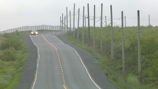 广角乡村道路。道路两旁可见围栏、电线杆和电线。汽车驾驶可见。警车可见。视频素材