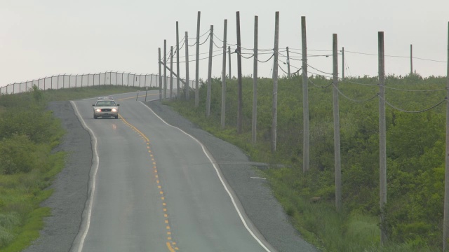 广角乡村道路。道路两旁可见围栏、电线杆和电线。汽车驾驶可见。警车可见。视频素材