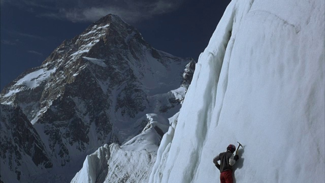 登山者用冰镐爬上积雪的山面。视频素材