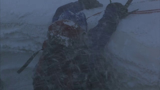 一个登山者在一个积雪的山脊边缘挣扎着要爬过去。视频素材