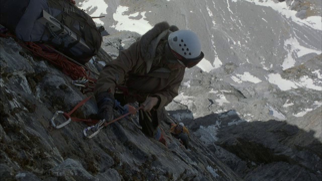 两位登山者正在攀登一面垂直的岩壁。视频素材