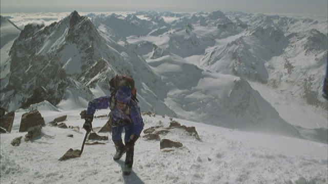 四位登山者艰难地爬上了一座白雪皑皑的山脊。视频素材