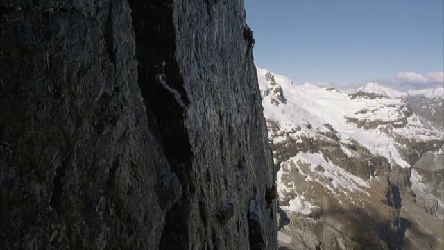 两个登山者正在攀登高山上的一面垂直的岩壁。视频素材