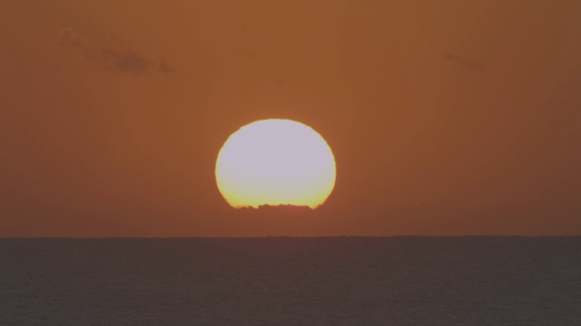 时间流逝，太阳在开阔的海面上从地平线上的云层升起视频素材