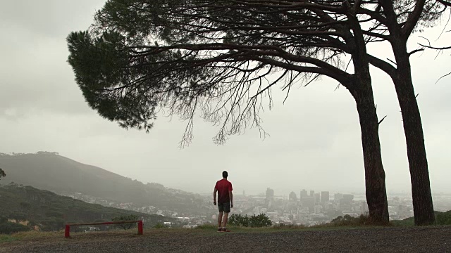 一个成熟的男人在城市上方的山上慢跑视频素材