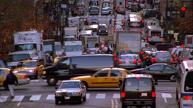 在十字路口/纽约市的汽车、卡车、出租车、公共汽车、自行车和行人视频素材