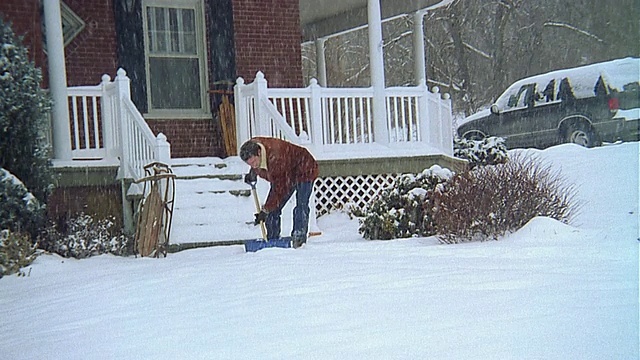 广角镜头男子铲雪从前面的步行/停止和摆姿势视频素材