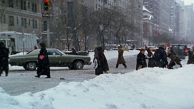 慢动作广角拍摄行人和交通在下雪的城市街道视频下载