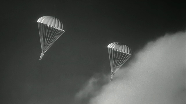 1940年合成宽镜头2玩具降落伞下落/云的背景视频素材