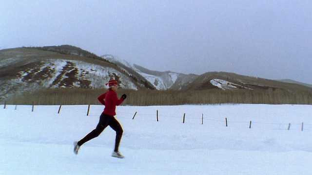 中镜头女子慢跑在雪道上/山和树的背景/韦尔，科罗拉多州，美国视频素材