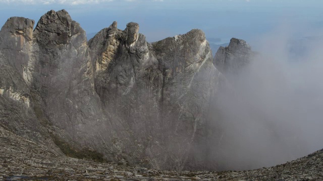 在婆罗洲基纳巴卢山的岩石山峰上，流逝的云滚滚而过视频素材