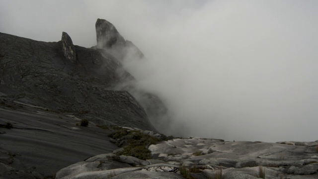 在婆罗洲基纳巴卢山，时断时落的云笼罩着岩石山峰视频素材