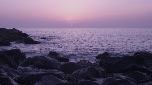 阿曼，日落时海浪拍打着岩石海滩视频素材