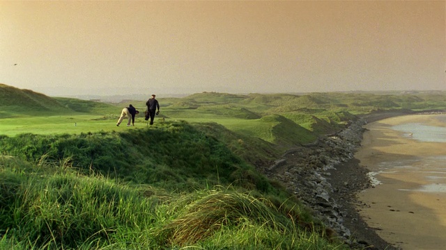 从水到高尔夫球手和球童在高尔夫球场/ Ballybunion，爱尔兰视频下载