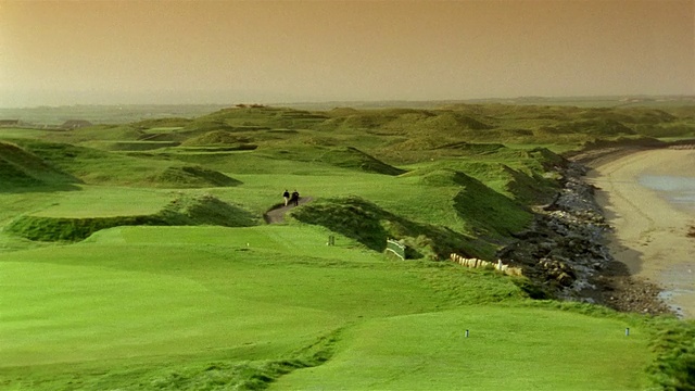 宽击球盘水到球道/高尔夫球手和球童沿着小径/ Ballybunion，爱尔兰视频素材