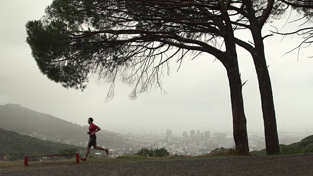 一个成熟的男人在城市上方的山上慢跑视频素材