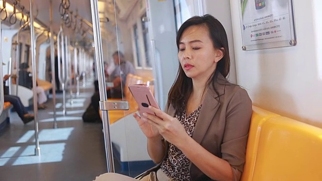 商务女性在城市火车上使用智能手机视频下载